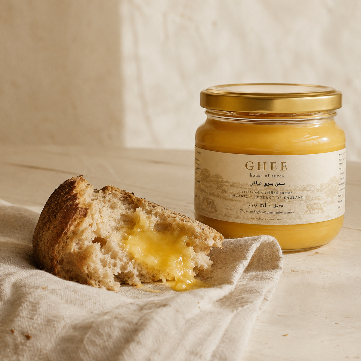 Jar of House of Aurea ghee beside torn bread on a linen cloth